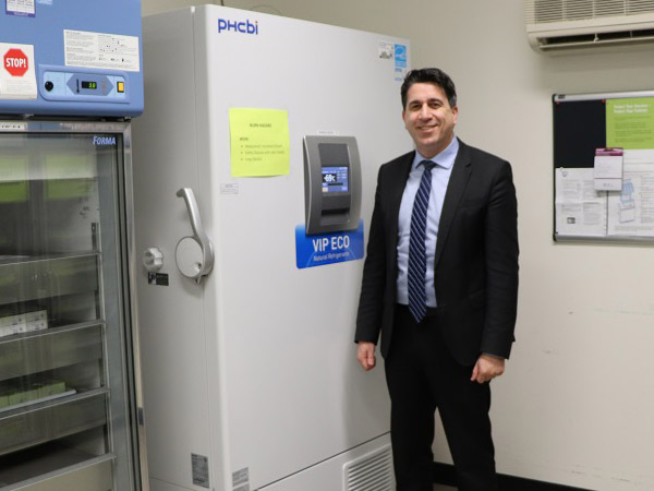 MOH Dr. Ian Arra stands beside vaccine cryogenic freezer