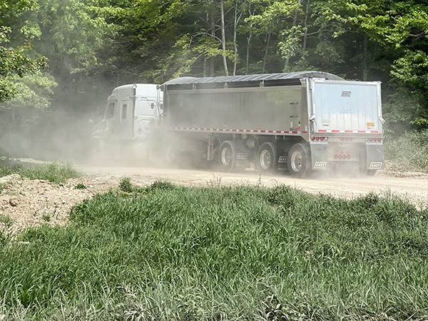 Truck going into the dump on dusty road.