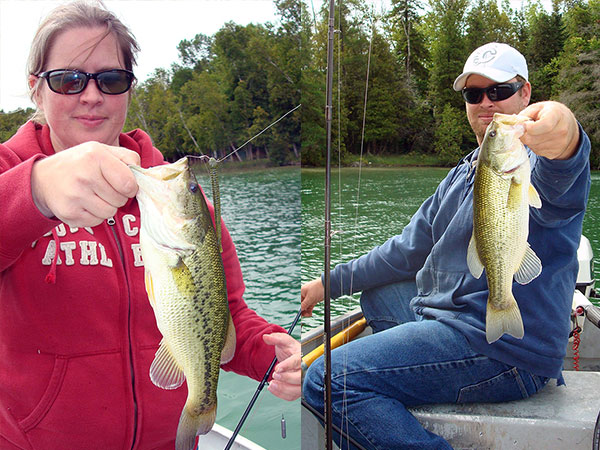 Man and woman holding their fish after catching them.