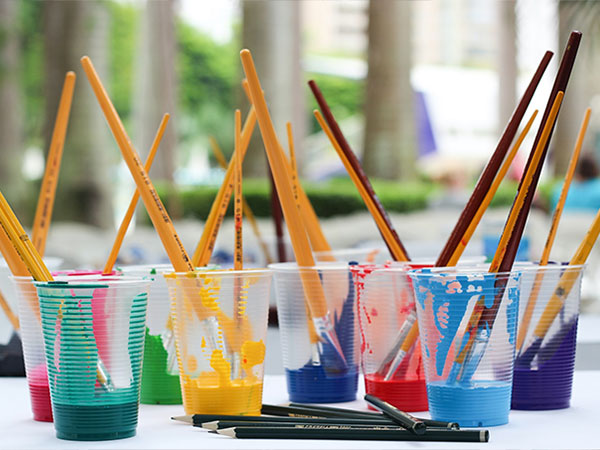brushes in cups with different colours of paint.