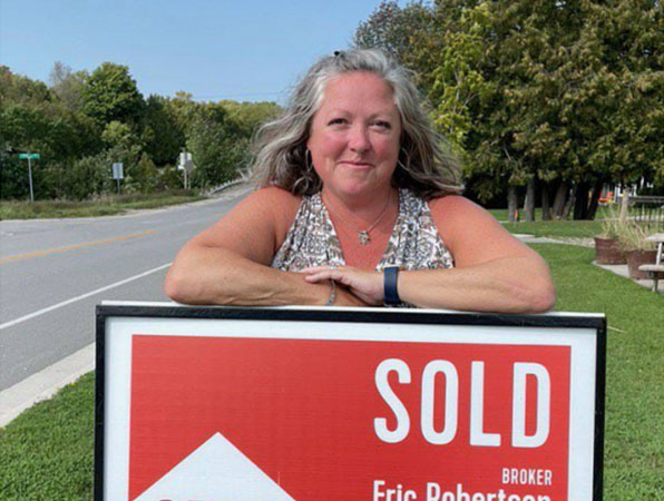Mandi Russell leaning on real estate sign