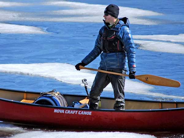 Adam Shoalts standing in a canoe in the Canadian Arctic