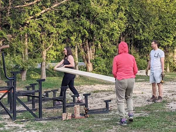 Volunteers carry wood to the bleacher framework